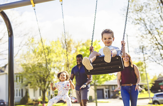 A little boy smiling while being pushed on a swing
