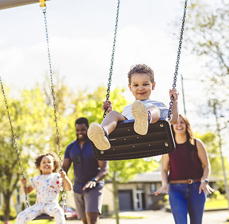 A little boy smiling while being pushed on a swing