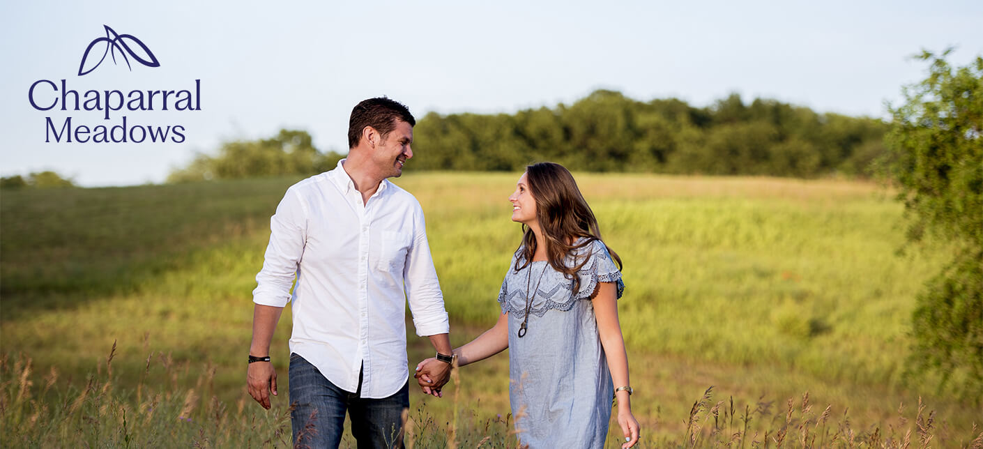 A couple holding hands while walking through a field