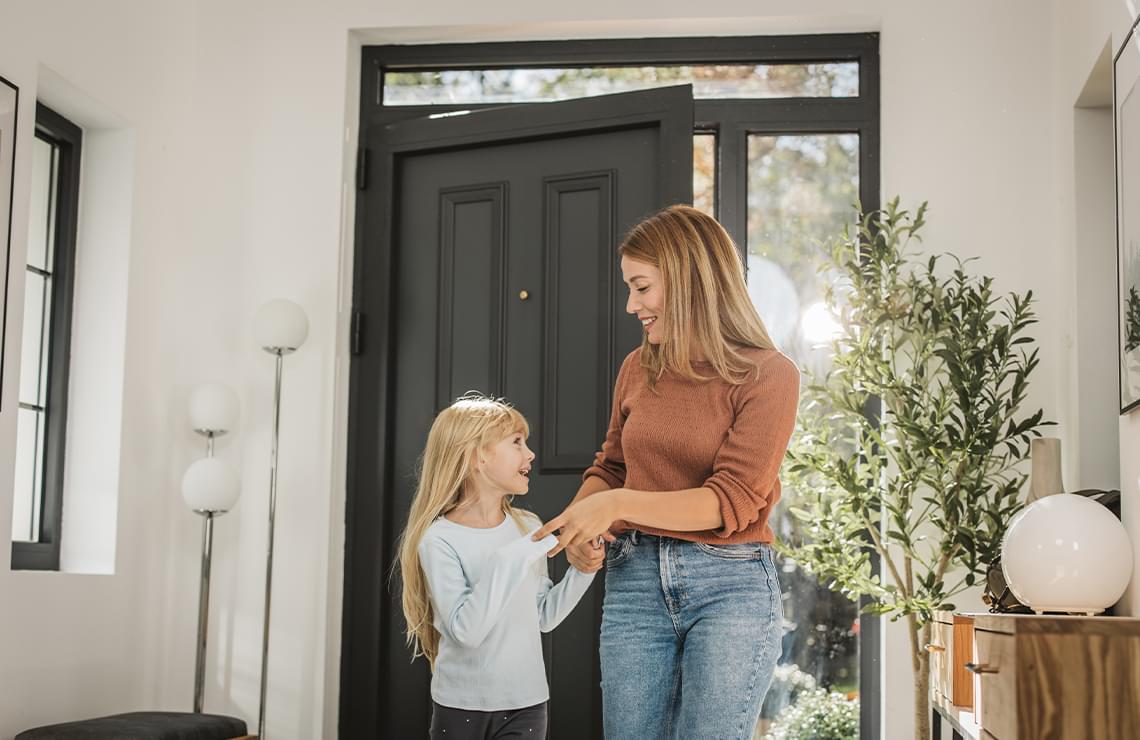 Mother and daughter walking into front door of their home