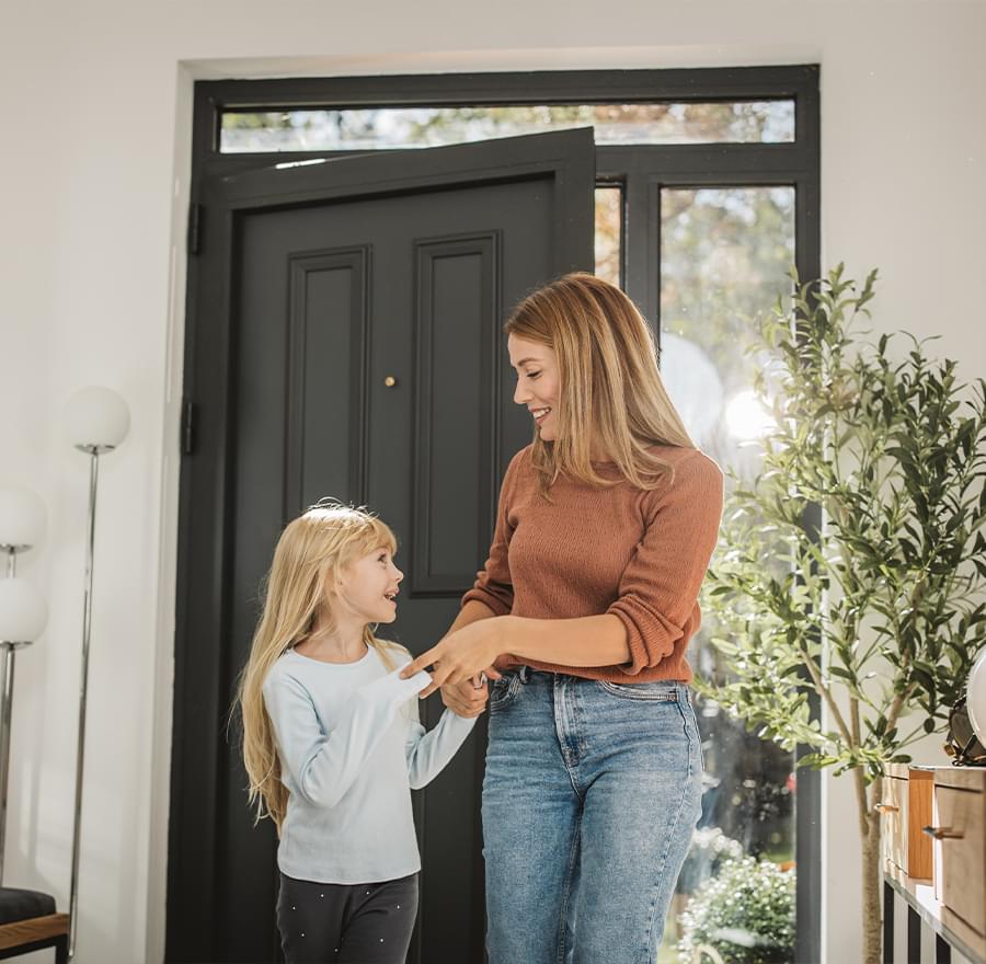 Mother and daughter walking into front door of their home