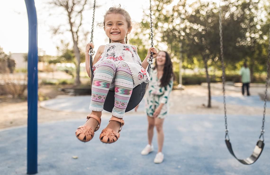 Mother pushing her daughter on a swing