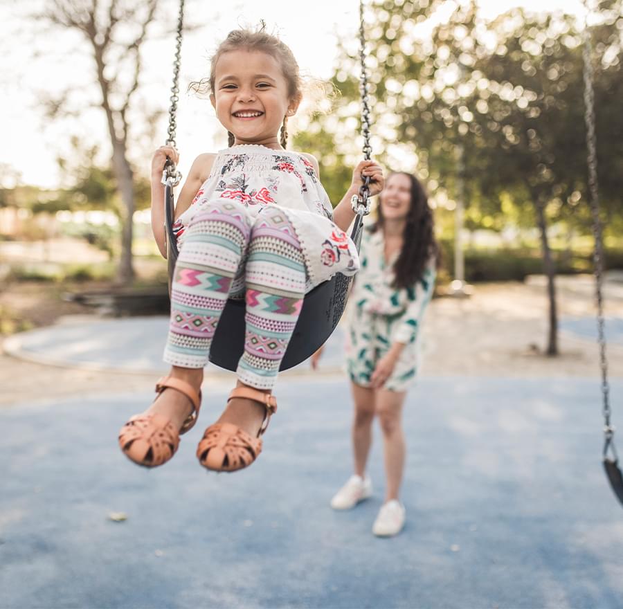 Mother pushing her daughter on a swing